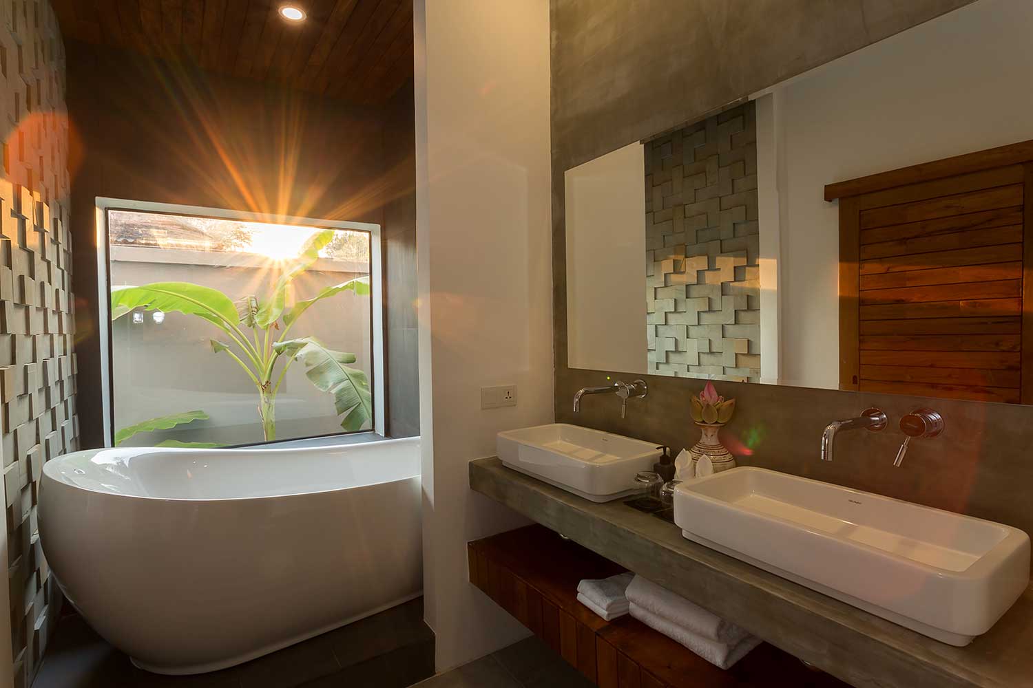 Luxury hotel bathroom featuring a freestanding soaking tub and a garden window at sunrise.