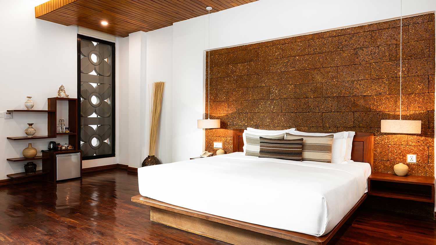 Premium Room bed with a decorative textured feature wall and warm wood ceiling.