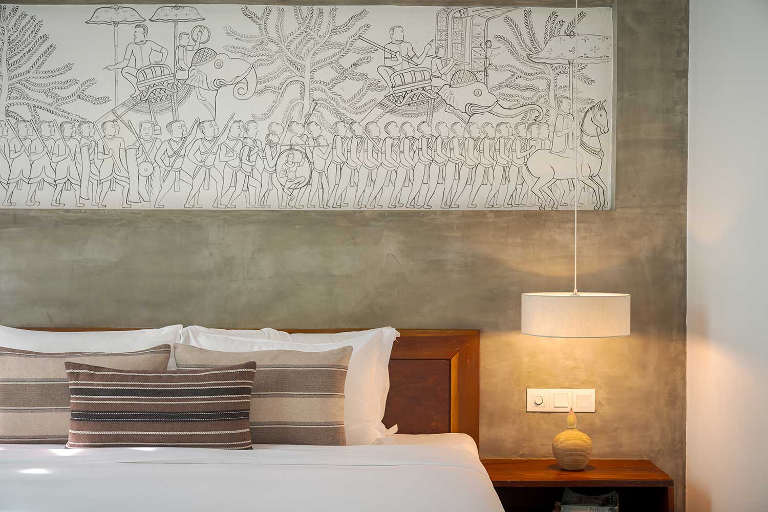 Bedroom of the Royal Suite at Shintana Saya Residence featuring a carved Angkor-inspired wall mural and luxury bedding.