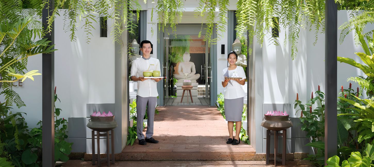 Two staff members in traditional uniforms welcoming guests at the entrance of Shintana Saya Residence in Siem Reap.